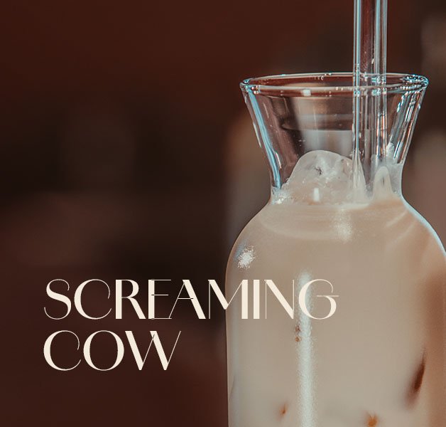  Glasflasche mit hellbraunem ECKES Screaming Cow Cocktail und Eiswürfeln.