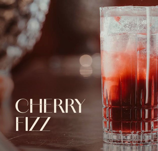 Glas mit ECKES Cherry Fizz Cocktail auf Eis, vor einem dunklen Hintergrund mit der Aufschrift "Cherry Fizz".