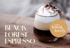Ein elegantes Glas mit Black Forest Espresso, geschichtet mit Sahne und Schokoladenraspeln, auf einem Holzuntergrund.