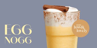 Ein Glas Eggnog mit einer Schicht Sahne und Zimtstange, dekoriert mit einer Prise Zimt auf der Oberseite.