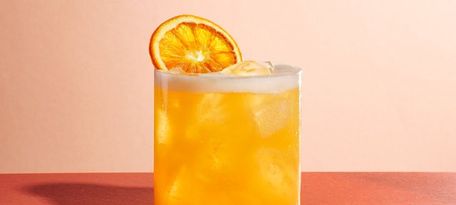 Säuerlicher Peach Sour Cocktail mit ECKES Weißer Pfirsich Likör, Zitronen- und Orangensaft, serviert auf Eis und garniert mit einer frischen Orangenscheibe.
