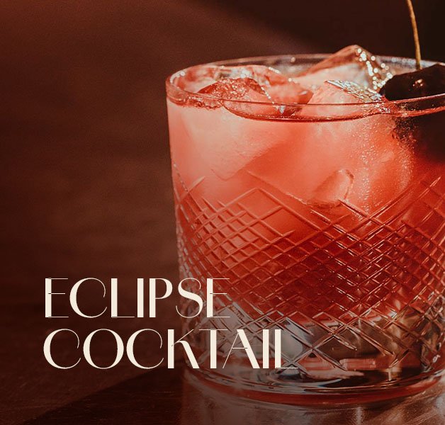 Glas mit ECKES Eclipse Cocktail auf Eis, garniert mit einer Kirsche, vor einem dunklen Hintergrund