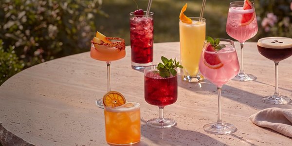 Acht unterschiedlich dekorierte Cocktails in verschiedenen Gläsern auf einem 