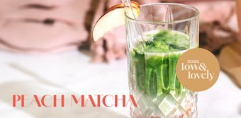 Ein erfrischendes Getränk aus Matcha und Pfirsich, serviert in einem eleganten Glas mit einem Apfelschnitz als Dekoration.