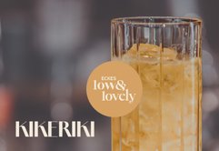 Ein elegantes Glas mit einem gelben Getränk und Eiswürfeln, das in einem modernen, verschwommenen Raum präsentiert wird.