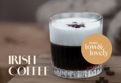 Ein Glas Irish Coffee mit einer cremigen Schicht Sahne und Kaffeebohnen auf der Oberfläche, auf einem Holztisch platziert.