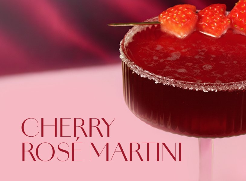 Ein eleganter Cherry Rosé Martini in einem stilvollen Glas, garniert mit frischen Erdbeeren und einem Zuckerrand.