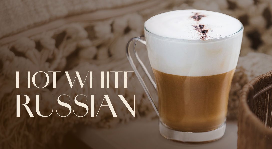 Glastasse mit Hot White Russian, einer Schaumkrone und drei Kaffeebohnen als Garnitur.