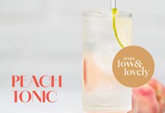 Ein stilvolles Pfirsich-Tonic-Getränk, das in einem eleganten Glas serviert wird, mit einer dekorativen Fruchtspirale.