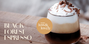 Ein elegantes Glas mit Black Forest Espresso, geschichtet mit Sahne und Schokoladenraspeln, auf einem Holzuntergrund.