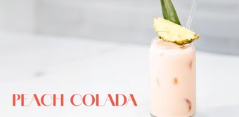 Ein köstlicher Peach Colada, serviert in einem Glas mit Eis, verziert mit einer frischen Ananasscheibe und einem Strohhalm.