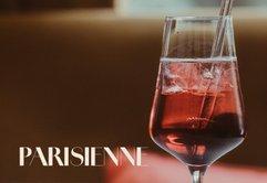 Ein elegantes Glas mit einem roten Getränk, gefüllt mit Eiswürfeln, steht auf einem Tisch in einem stilvollen Ambiente.