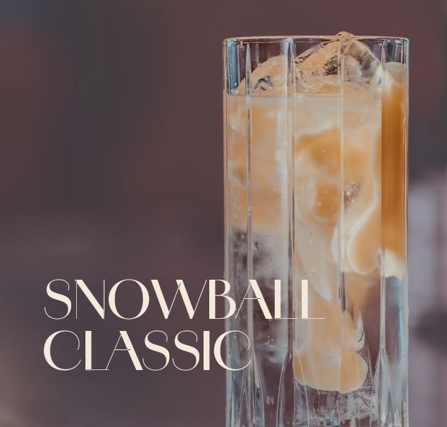 Glas mit ECKES Snowball Classic Cocktail auf Eis, garniert mit einer Zitronenzeste
