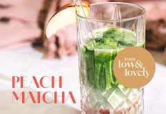 Ein erfrischendes Getränk aus Matcha und Pfirsich, serviert in einem eleganten Glas mit einem Apfelschnitz als Dekoration.