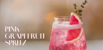 Ein stilvolles Getränk in einem klaren Glas, gefüllt mit pinkem Spritz und dekoriert mit einer Grapefruit-Scheibe.
