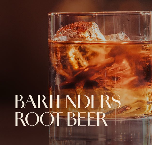 Tumbler-Glas mit dunklem ECKES Bartender's Root Beer Cocktail und großen Eiswürfeln.