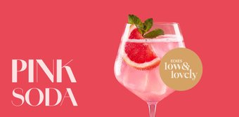 Elegantes Pink Soda im Glas mit Zitrusring, Erdbeere und Minzblättern als Garnitur auf rosafarbenem Untergrund.