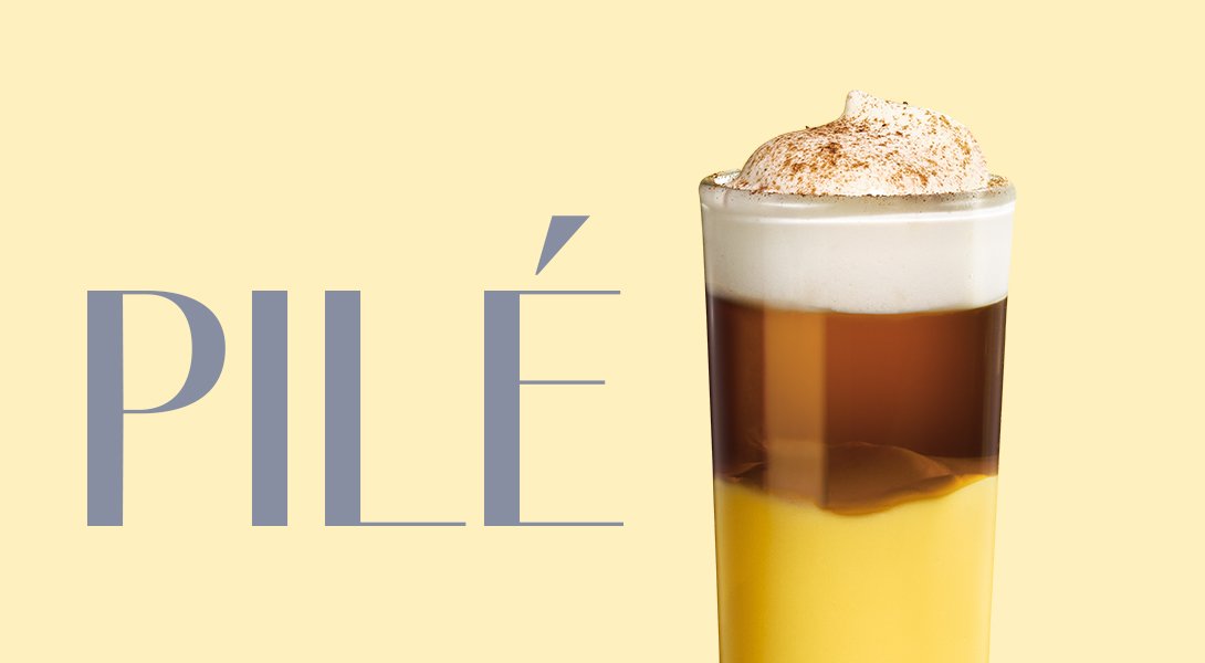 Glas mit geschichtetem Cocktail aus gelbem Likör und dunklem Kaffee, mit Sahnehaube bestreut.