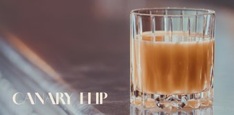 Ein klarer, facettierter Becher mit einem köstlichen, hellbraunen Getränk, das auf einem polierten Tisch steht.