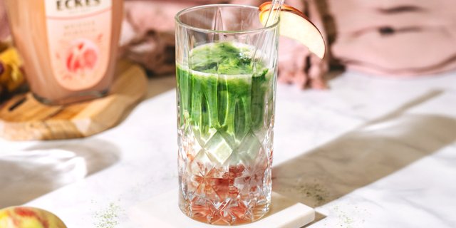 Peach Matcha Cocktail mit Pfirsichscheiben und Matcha-Topping in einem Glas