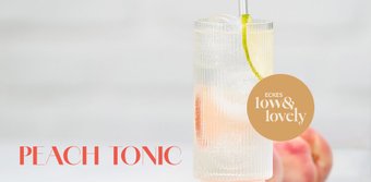 Ein stilvolles Pfirsich-Tonic-Getränk, das in einem eleganten Glas serviert wird, mit einer dekorativen Fruchtspirale.