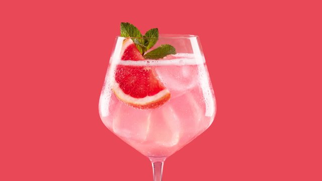 Ein erfrischendes Getränk in einem eleganten Glas, garniert mit einer Scheibe Grapefruit und frischen Minzblättern.