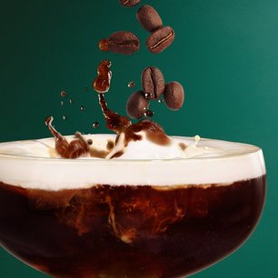 Nahaufnahme eines Kaffeelikörs in einem Cocktailglas mit aufsteigenden Kaffeebohnen