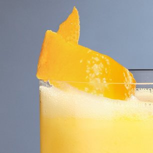  Nahaufnahme eines Eierlikör-Drinks in einem Glas mit Orangenschale als Garnitur.